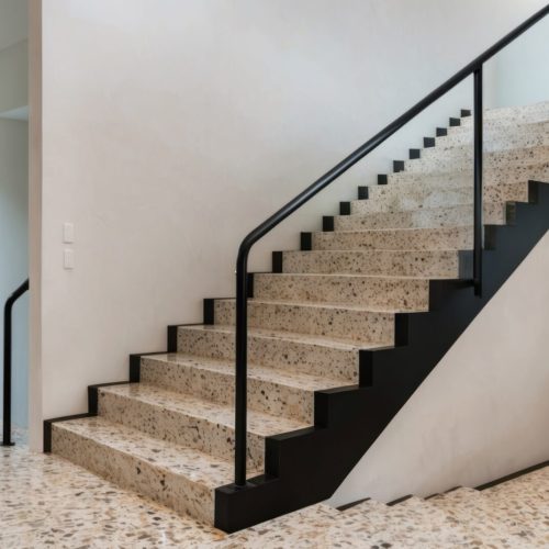 A modern terrazzo staircase featuring elegant black railing in a stylish interior